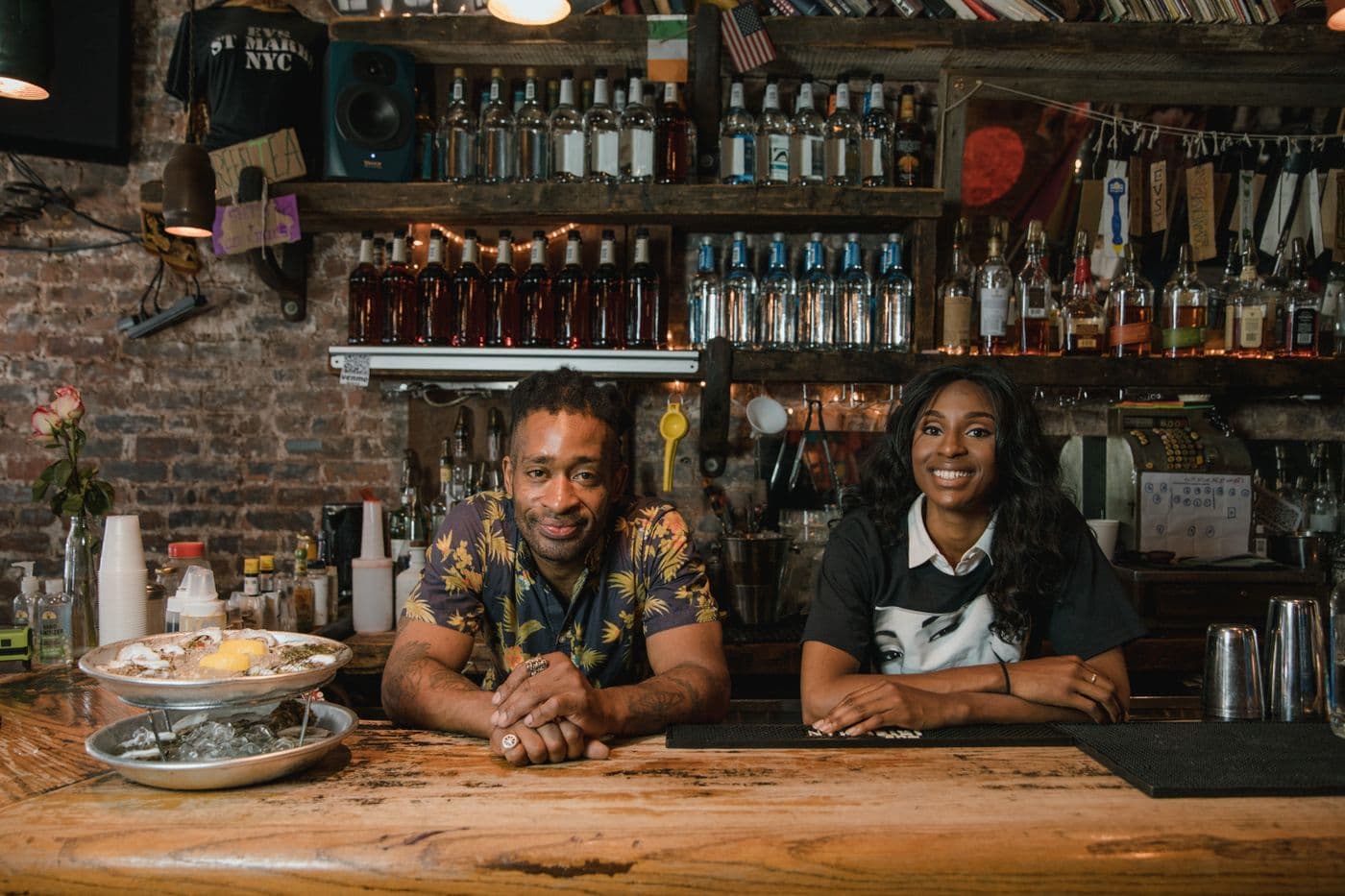 Deux gérants souriants derrière le comptoir de leur bar-restaurant